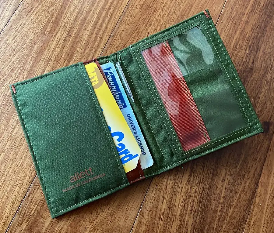 green hybrid wallet filled with cards on a desk