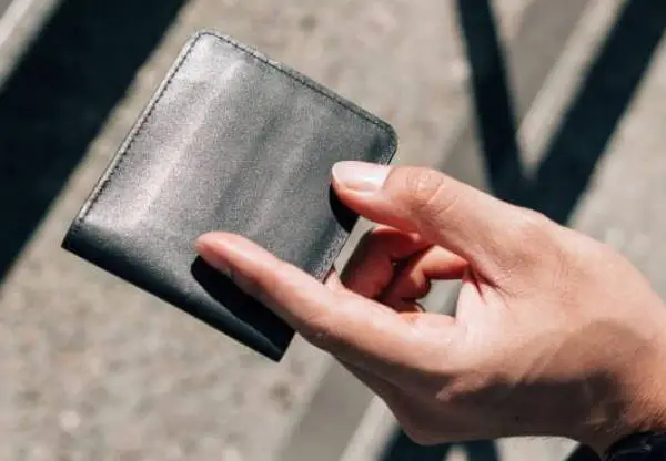 person holding an Airo Collective Stealth Leather wallet with just two fingers