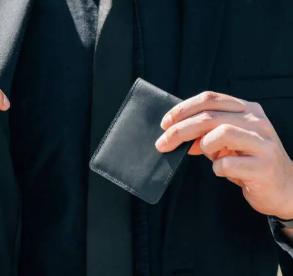 person in a suit holding an airo collective stealth leather wallet
